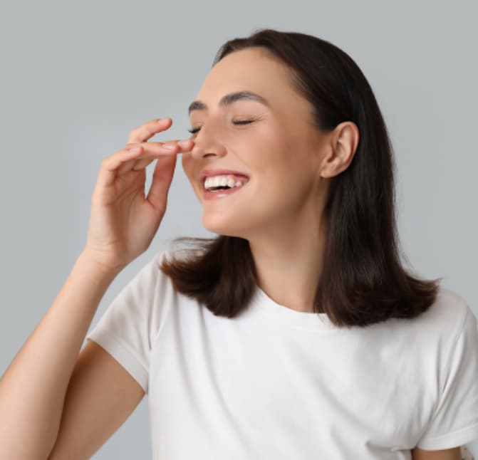 Smiling patient gently touching the nose after crooked nose surgery to correct nasal deviation
